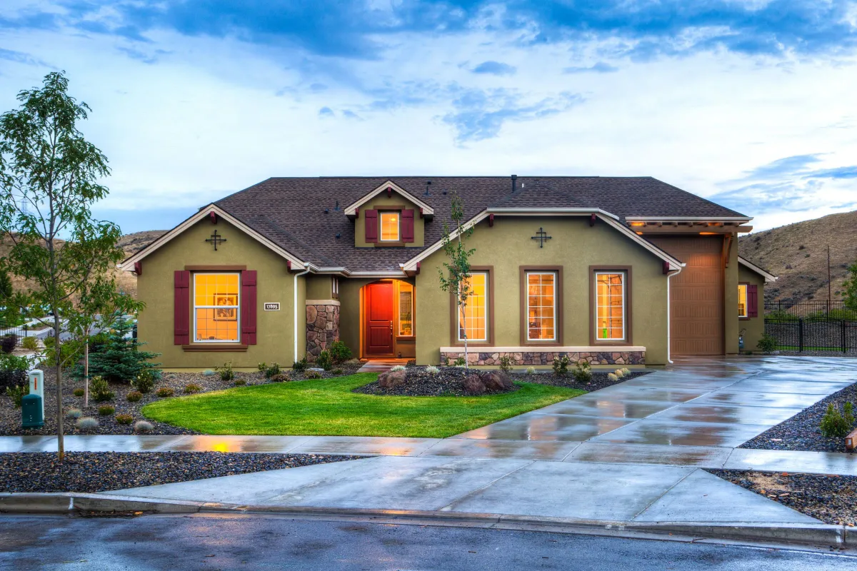 Illustrative stock photo: landscaped single-story home with illuminated windows at dusk