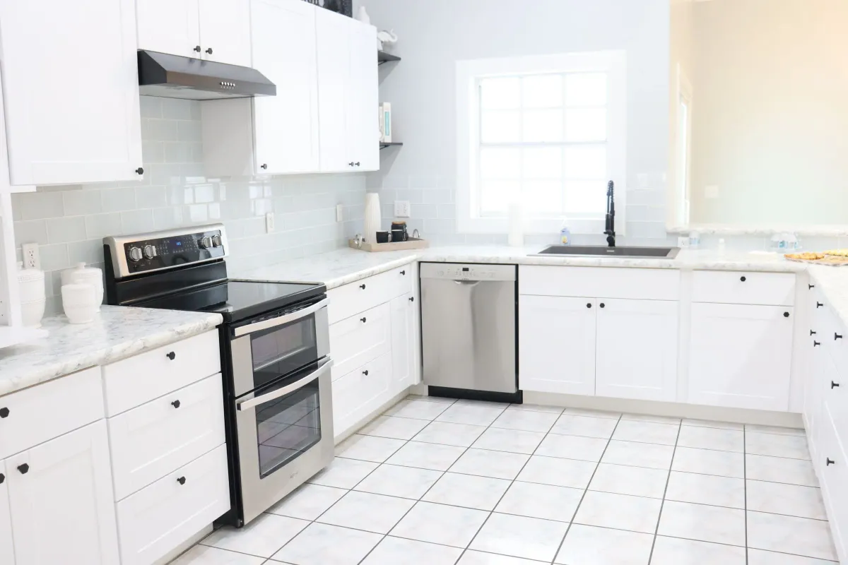 Illustrative stock photo: clean white kitchen with tiled flooring and clear counters