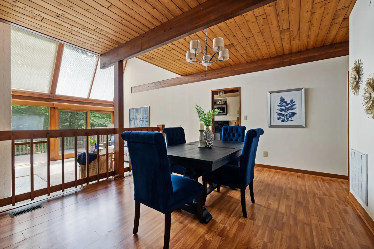 Illustrative stock photo: dining room with blue chairs, large windows and a timber ceiling