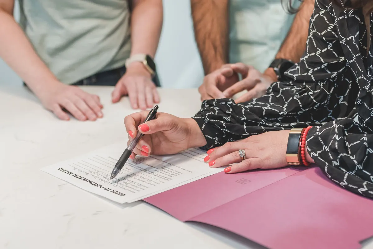 Illustrative stock photo: people reviewing and signing a property document at a table