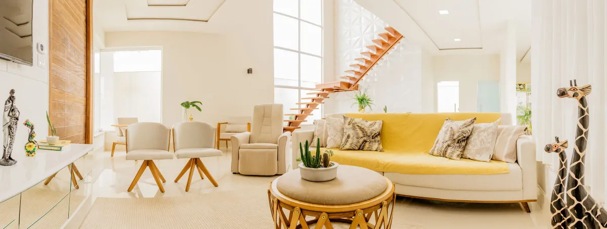 Illustrative stock photo: bright open-plan living room with a yellow sofa and wooden staircase