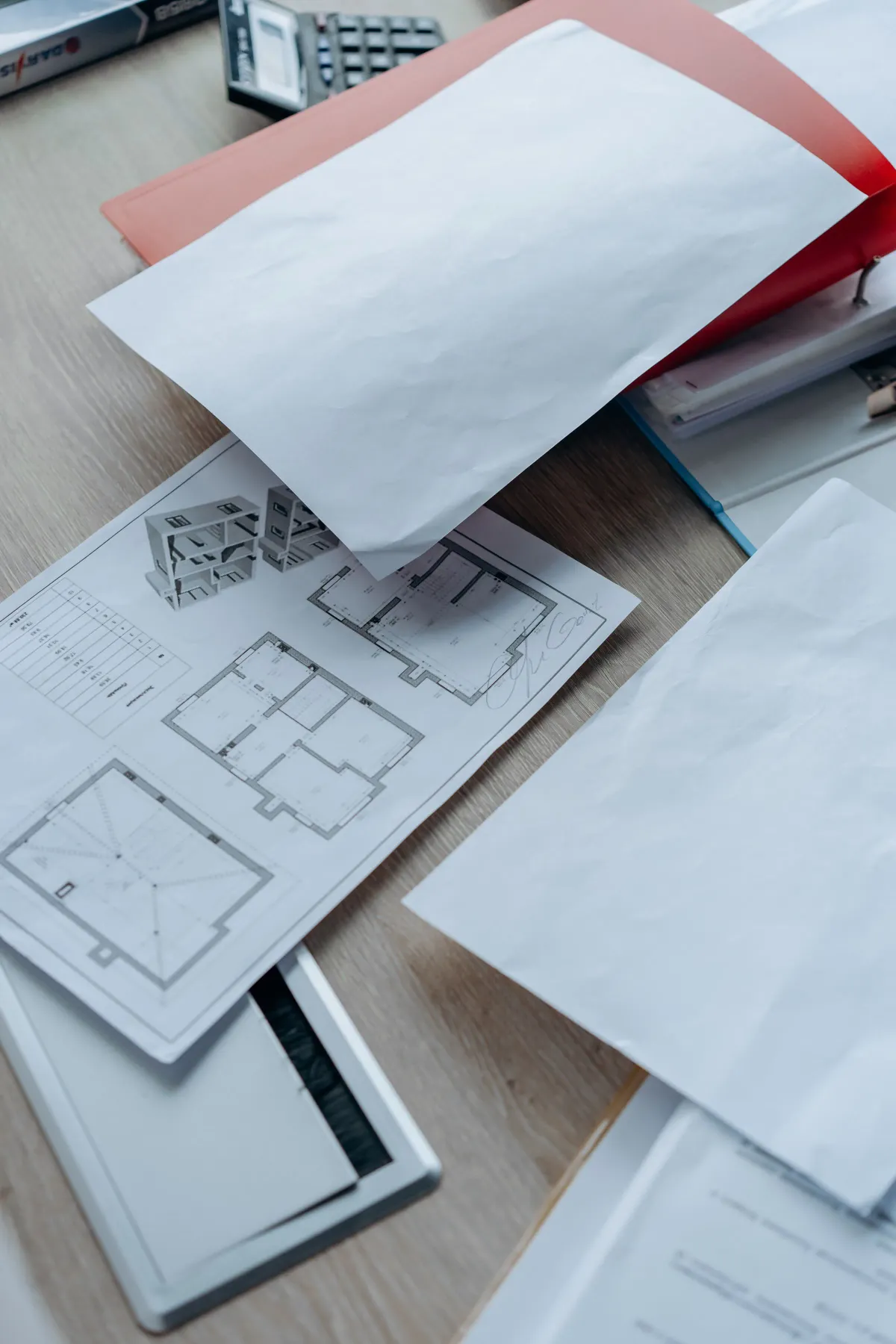 Illustrative stock photo: architectural floor plans and paperwork spread across a desk