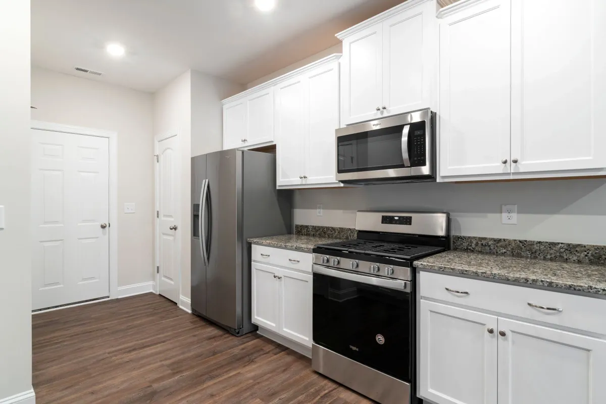 Illustrative stock photo: white kitchen with stainless steel appliances and wood-look flooring