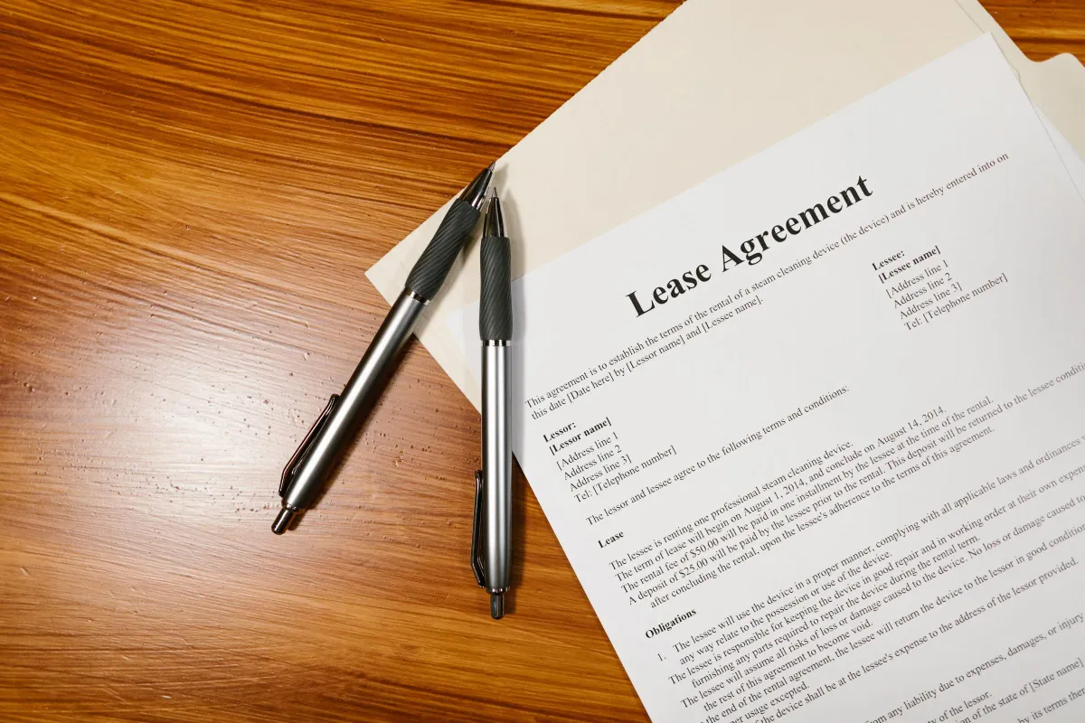 Illustrative stock photo: lease agreement and pens on a wooden tabletop